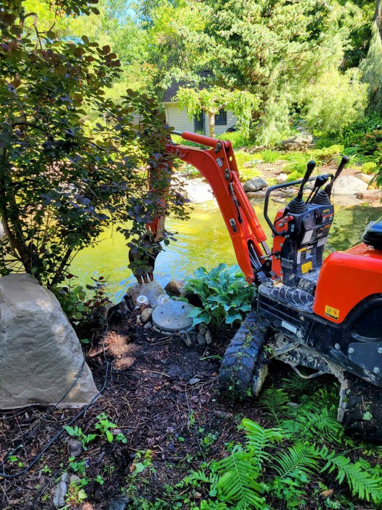 mini excavator next to Minnesota pond for repair